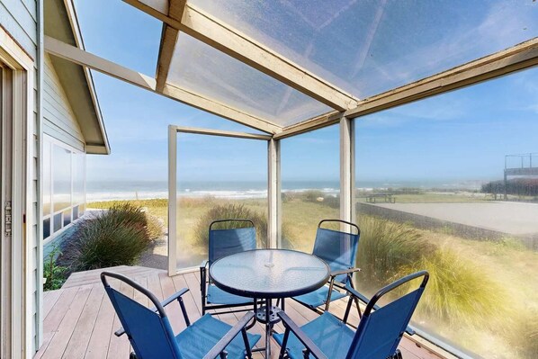 Veranda coperta con tavolo e sedie, con vista sulla spiaggia e sull'oceano.