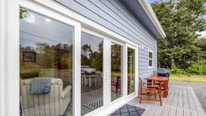 A deck with outdoor furniture, a sliding glass door leading to a covered patio area, and a view of a vehicle in the background.