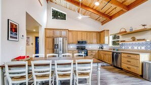 A modern kitchen with wooden cabinets, a stainless steel refrigerator, and a dining area with white chairs.