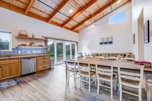 Un'ampia cucina con mobili in legno, lavastoviglie e zona pranzo con tavolo e sedie in legno.