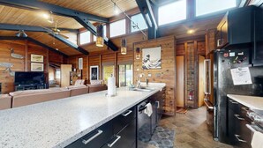 A spacious kitchen with a long countertop, wooden walls, and modern appliances. - Tideaway Private Hot Tub and Expansive Ocean View (Fort Bragg)