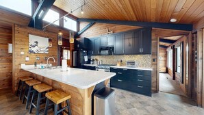 A modern kitchen with a large island, dark cabinets, and a wooden ceiling. - Tideaway Private Hot Tub and Expansive Ocean View (Fort Bragg)