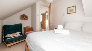 A bedroom with a bed, a chair, a bedside table, a lamp, and a picture on the wall. - Ve-Marn Cottage | Kilrenny (Kilrenny)