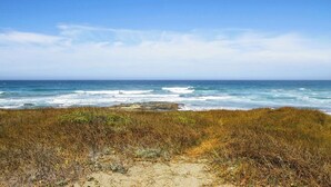 Ein Strand mit freiem Blick auf den Ozean und Felsformationen.