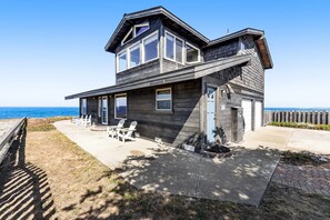 A two-story wooden house with a patio, outdoor seating, and a view of the ocean. - Oceanfront Sanctuary - Private Cove, Deck, Grill (Fort Bragg)