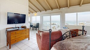 Un dormitorio con cama, televisor, cómoda de madera y vista a la playa.