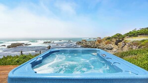 Un jacuzzi con vista al océano y a la costa rocosa.