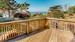 Eine Holzterrasse mit Blick auf das Meer und umliegende Bäume.