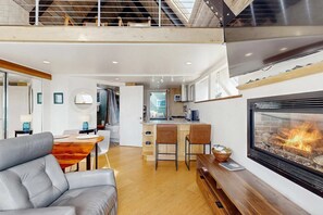 A modern interior with a fireplace, a dining area, and a kitchen. - Spectacular Oceanfront Studio with Hot Tub & Loft (Fort Bragg)