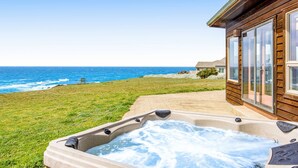 Une cabane en bois avec un jacuzzi et vue sur l’océan.