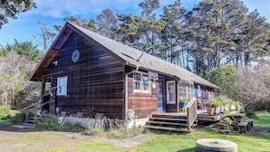 Une cabane en bois rustique, dotée d’une véranda, de marches et d’une petite terrasse.