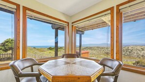Comedor con una mesa grande y cuatro sillas, ventanas amplias con vistas a un paisaje desértico.