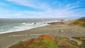 Un paisaje costero con una playa arenosa, afloramientos rocosos y vegetación.