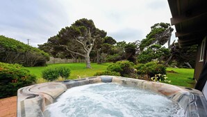 Ein Whirlpool in einem Garten mit Bäumen und einem gepflasterten Weg.