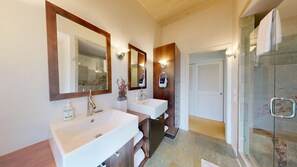 Une salle de bain avec deux lavabos, un grand miroir et une douche à parois de verre.