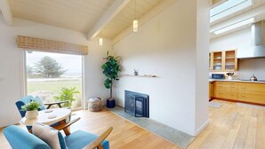 Ein modernes Wohnzimmer mit Kamin, Essbereich und Küche mit Holzausbau.