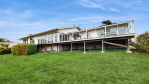 A modern two-story house with a flat roof, large windows, and a covered balcony. - Oceanfront Haven - Hot Tub & Private Beach Access (Fort Bragg)