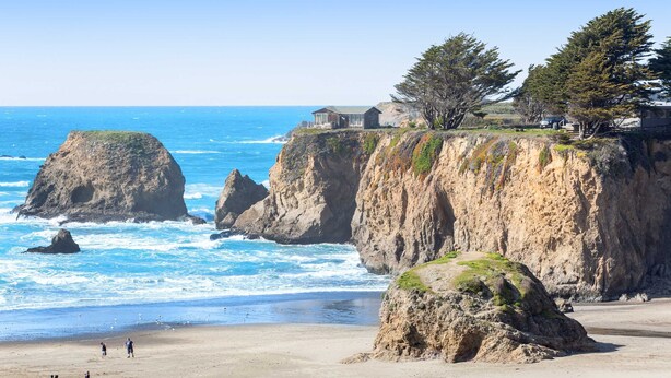 A coastal landscape with a beach, rocky cliffs, and a house on the cliff edge. - Oceanfront Haven - Hot Tub & Private Beach Access (Fort Bragg)