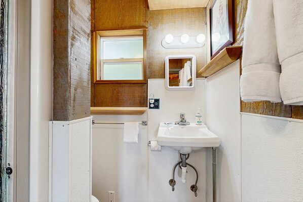 Une petite salle de bain avec un lavabo, un miroir et une fenêtre.