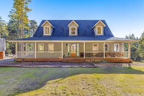 A two-story house with a covered porch, a front door, and a small front yard. - Stunning 3BR with ridge top views and hot tub (Little River)