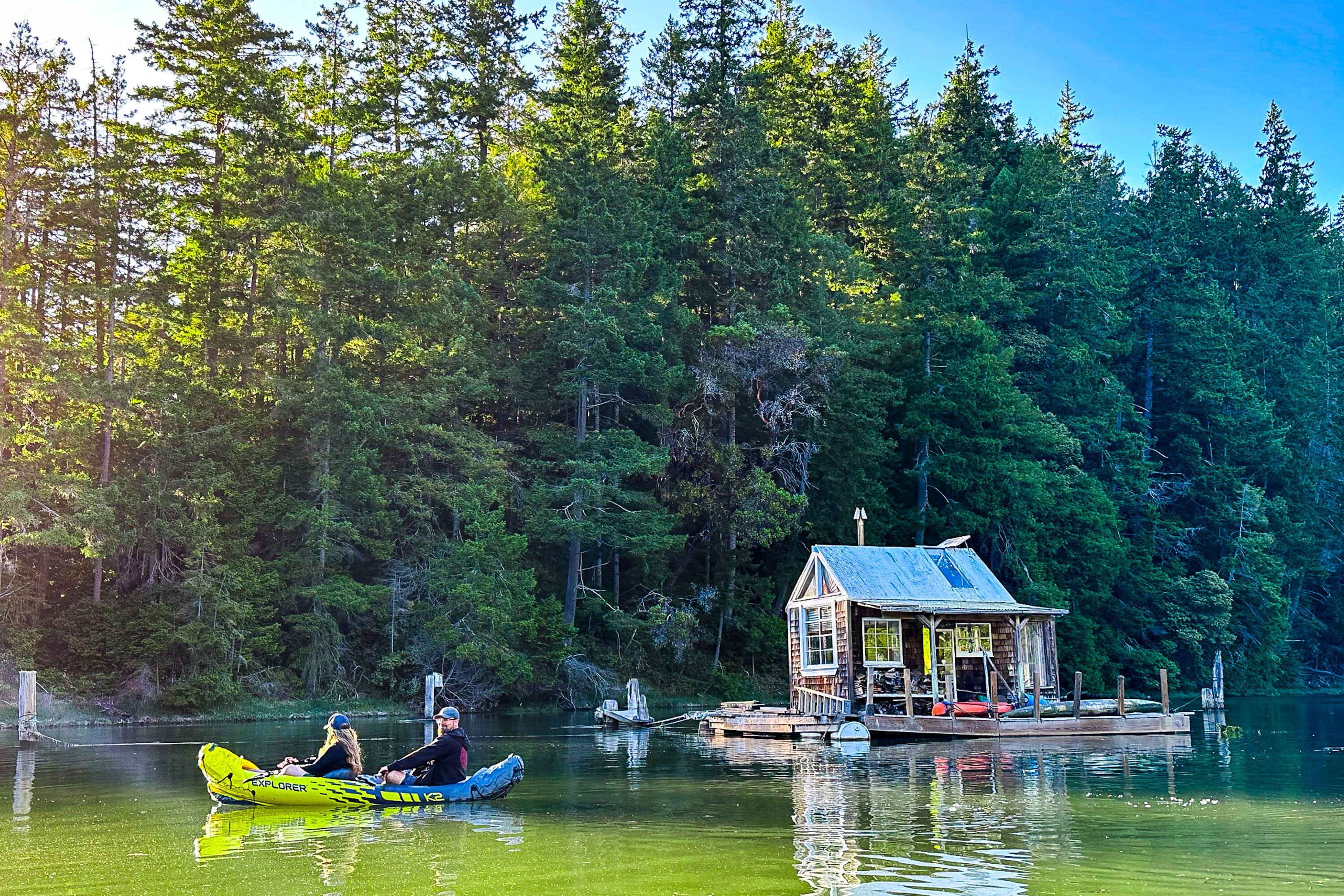 Eine Hütte an einem See, umgeben von dichtem Wald.