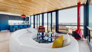 Una sala moderna con un sofá blanco, una mesa de centro de vidrio y una chimenea roja.