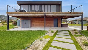 Una casa moderna de dos pisos con un porche cubierto, un garaje y un césped cuidado.