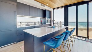 Una cocina moderna con una isla grande, taburetes de bar y vistas al océano.