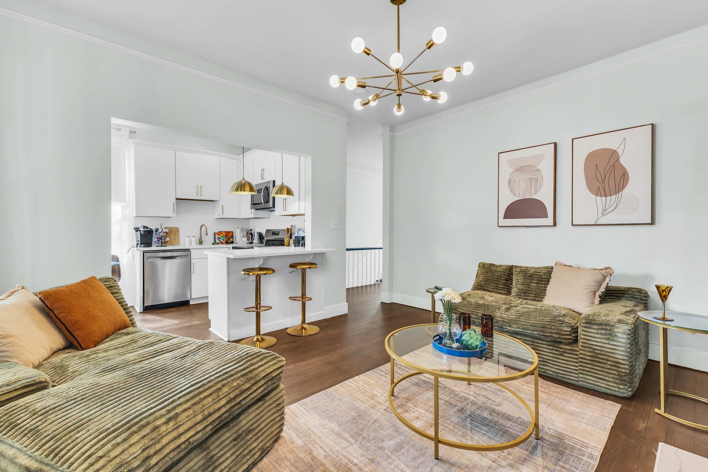 A modern living room with a sofa, coffee table, and a kitchen in the background.