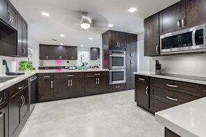 A modern kitchen with dark cabinetry, stainless steel appliances, and a central island. - Heated Pool, 2 Game Rooms + Outdoor Kitchen/Living (Hollywood)