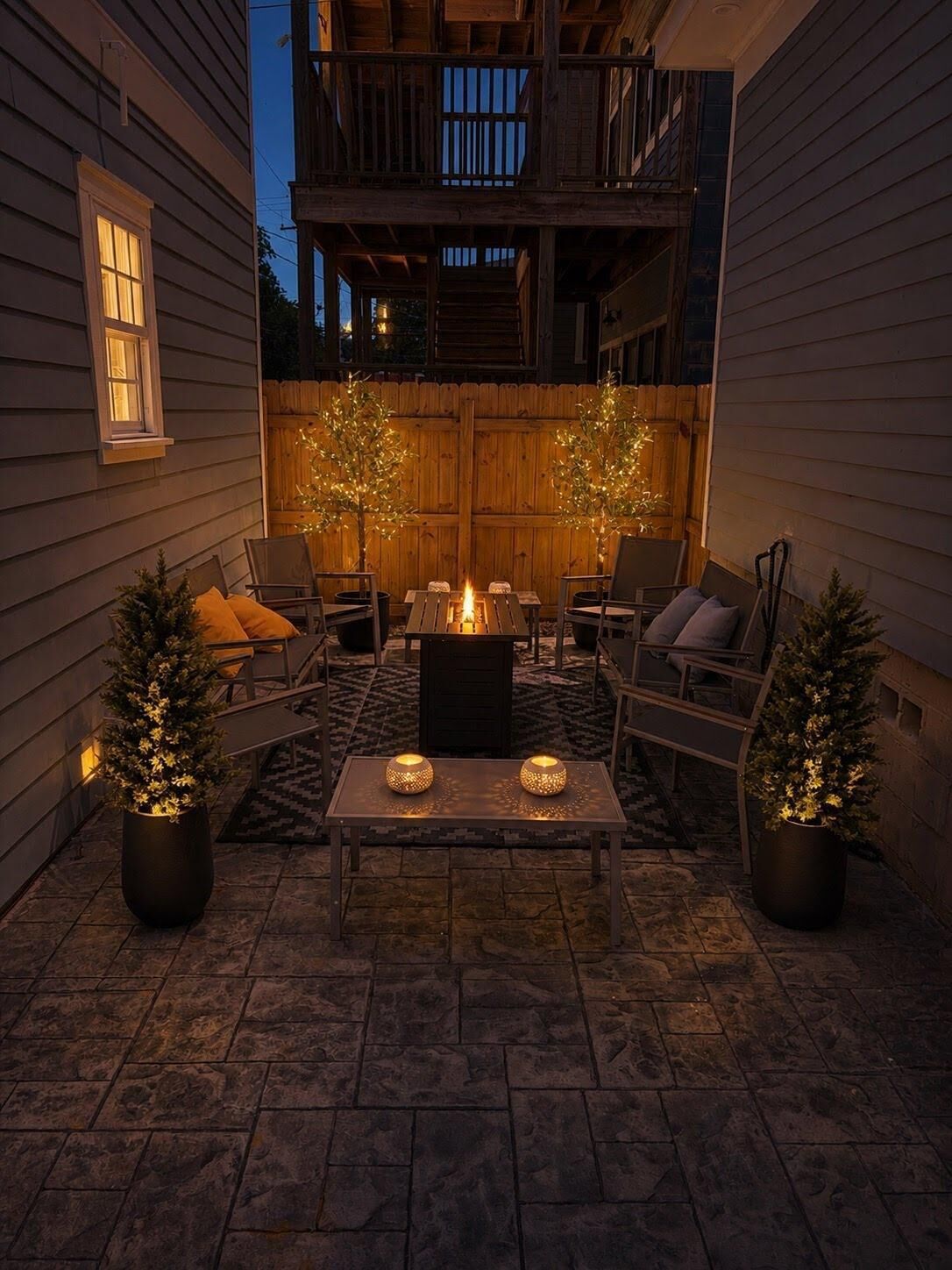 An outdoor patio with a fire pit, seating, and decorative lights.