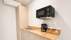 Une petite cuisine équipée d’un four à micro-ondes, d’une machine à café et d’un petit réfrigérateur.