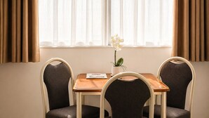 Une pièce avec une table et deux chaises, une plante en pot et un téléviseur fixé au mur.