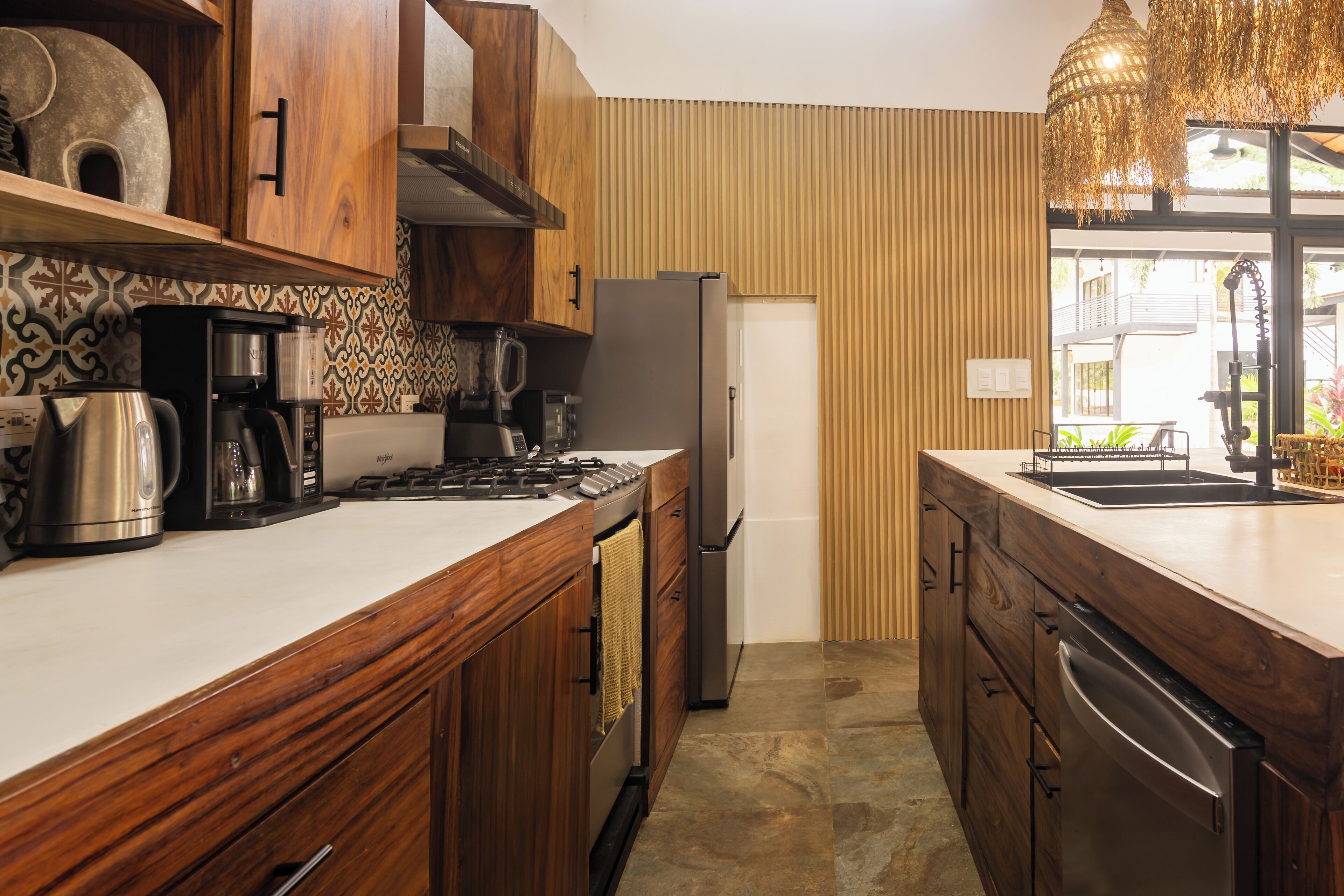 A modern kitchen with wooden cabinets, a stainless steel refrigerator, and a coffee maker.