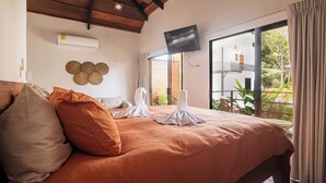 Un dormitorio con una cama grande, un televisor de pantalla plana en la pared y vistas al balcón exterior.
