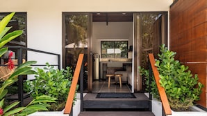 Una entrada moderna con una escalera de madera que conduce a una sala de estar con un sofá y una mesa de comedor.