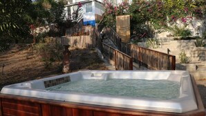 Ein Whirlpool in einem Garten mit Holzzaun, Treppe und einem Haus im Hintergrund.