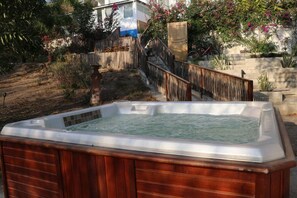 Ein Whirlpool in einem Garten mit Holzzaun, Treppe und einem Haus im Hintergrund.