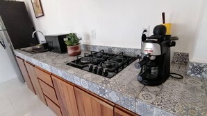 Eine Küche mit Gasherd, Kaffeemaschine und einer Topfpflanze.