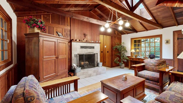Un intérieur chaleureux avec des éléments en bois, notamment une cheminée, des meubles en bois et une grande fenêtre.