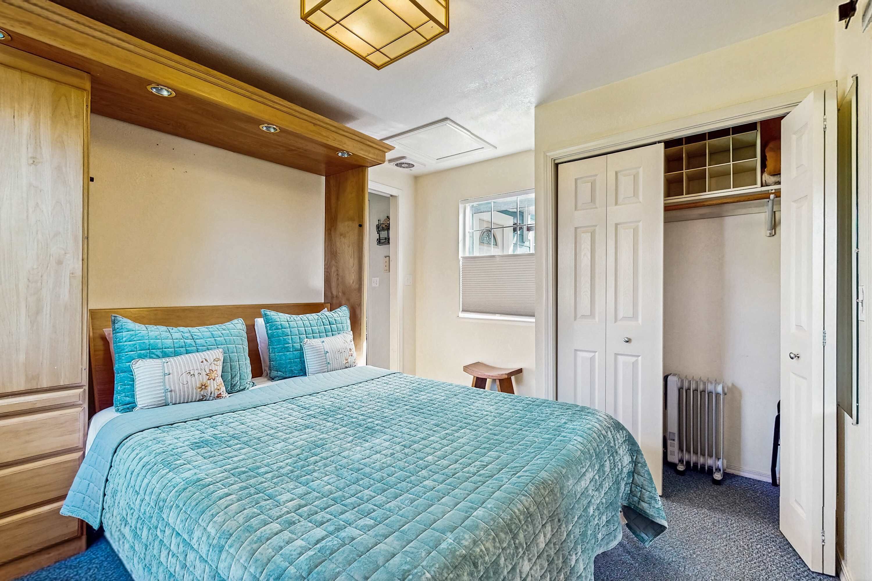 Een slaapkamer met een groot bed, een houten hoofdbord, een kast met een spiegel in volle lengte en een radiator.