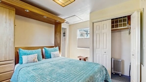 Un dormitorio con una cama grande, cabecera de madera, un armario con espejo de cuerpo entero y un radiador.
