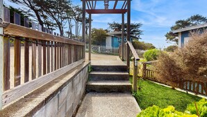 Una pérgola de madera con una escalera de piedra que lleva a una casa.