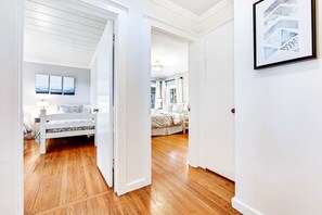 Ein Schlafzimmer mit Holzboden, einem Bett mit gemustertem Überwurf und einem Nachttisch mit Lampe.
