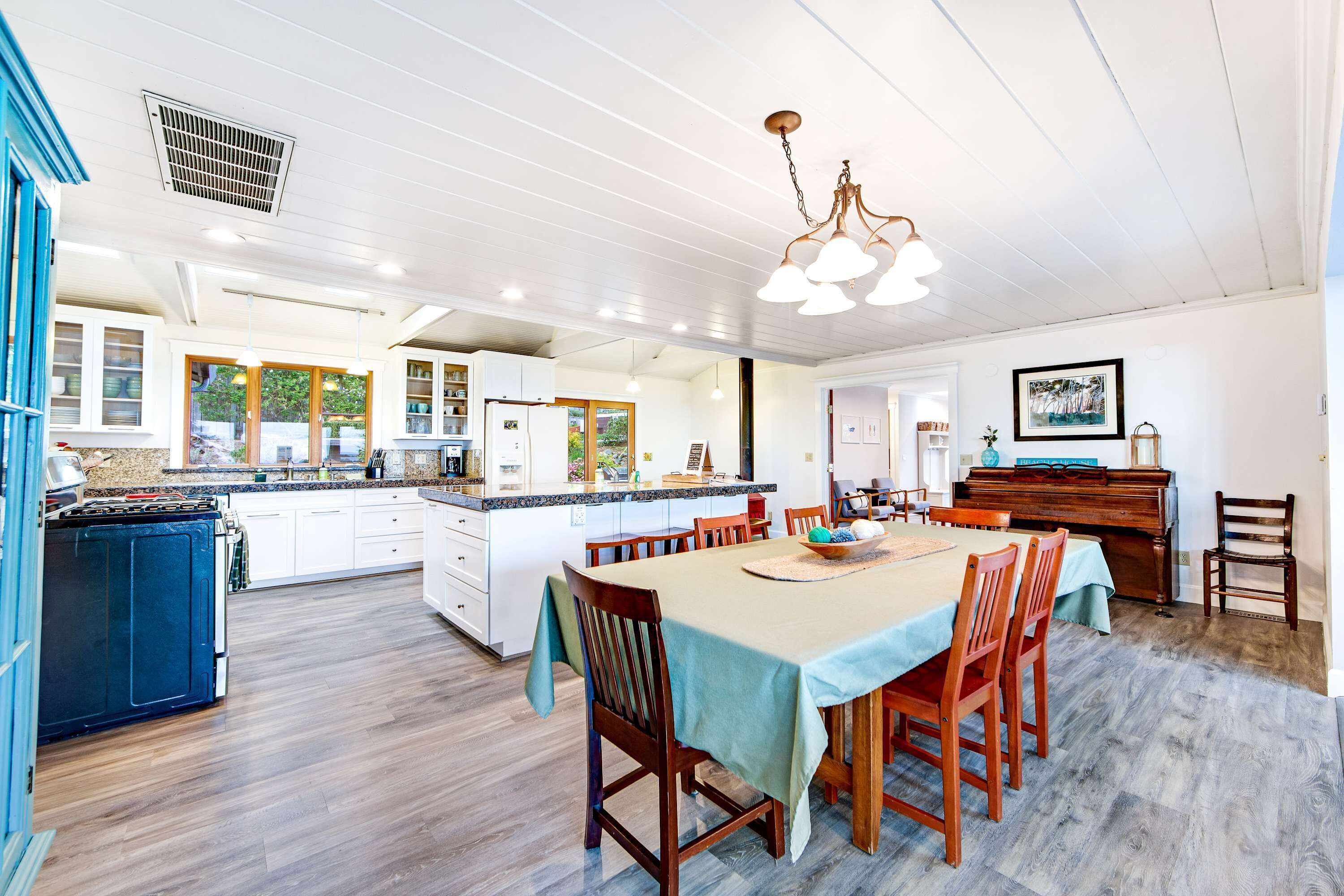 A spacious kitchen with white cabinets, a central island, and a dining area with a table and chairs.