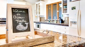 A kitchen with a chalkboard sign reading "Welcome to Ocean Trails" and a wooden tray.