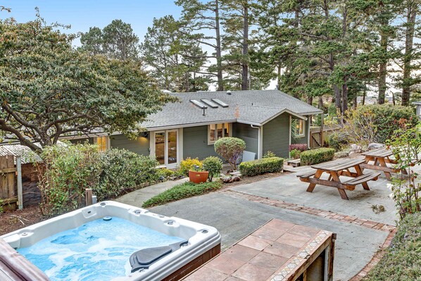 Ein Haus mit Hinterhof-Terrasse, Whirlpool und Picknicktischen.