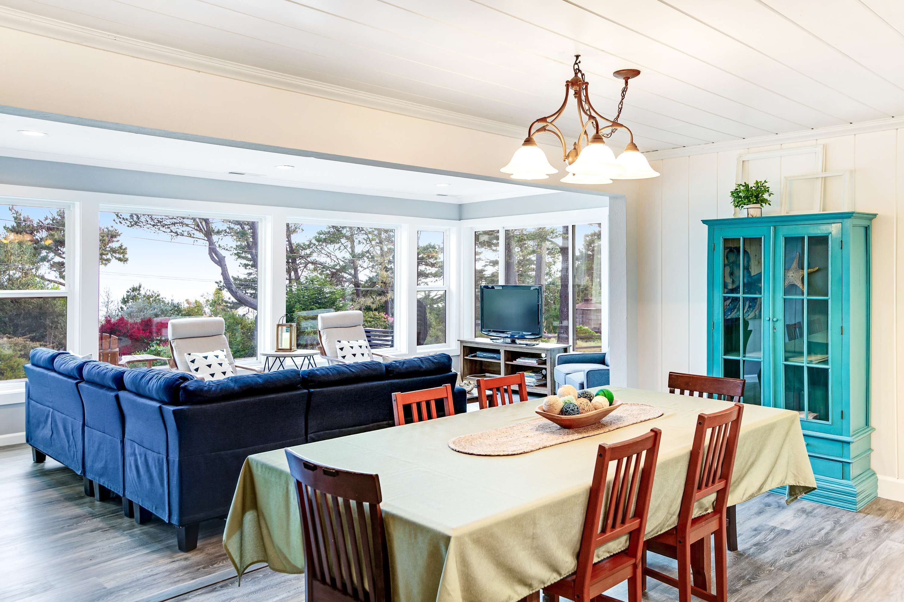 A spacious room with a large dining table, a blue sofa, and a teal cabinet.