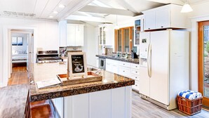 A modern kitchen with white cabinets, granite countertops, and a central island.