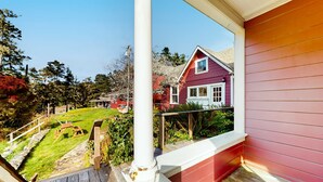 Un terrazzo in legno con vista su una casa rossa e un giardino erboso.